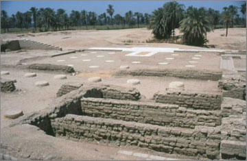 View of the central columned hall. The positions of the missing column bases are represented by circular pads made from a mixture of white stone chippings and white cement. The stonework in the background marks the outline of a staircase or ramp which led up to a platform. The orignal stone blocks had been removed at the end of the Amarna Period, but their impressions remained in layer of gypsum concrete