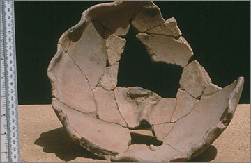 Bowl with a crinkled rim. The figure of a rearing cobra was originally modelled on the base of the bowl. The vessel might have been used in a ritual to protect the house from harmful spirits of the night
