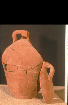 One of a group of nine similar pottery vessels from the monastery at Kom el-Nana (catalogue no. 424) in which a panel from the shoulder, with its own handle, has been separately made. All examples have a hole in the base and some have holes pierced on the shoulder. The purpose of these vessels is not known.